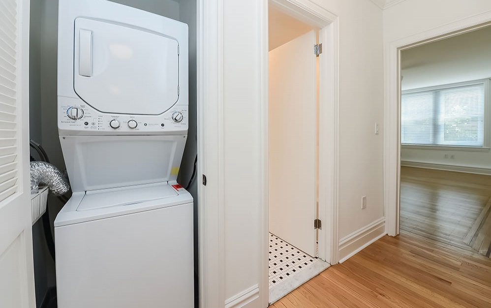 stacked washer/dryer unit in laundry room with bathroom