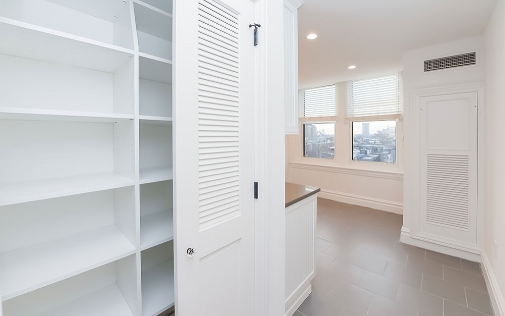 hall closet with built-in shelves next to kitchen